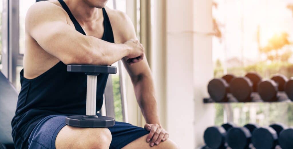 Man sitting and resting with a dumbbell.